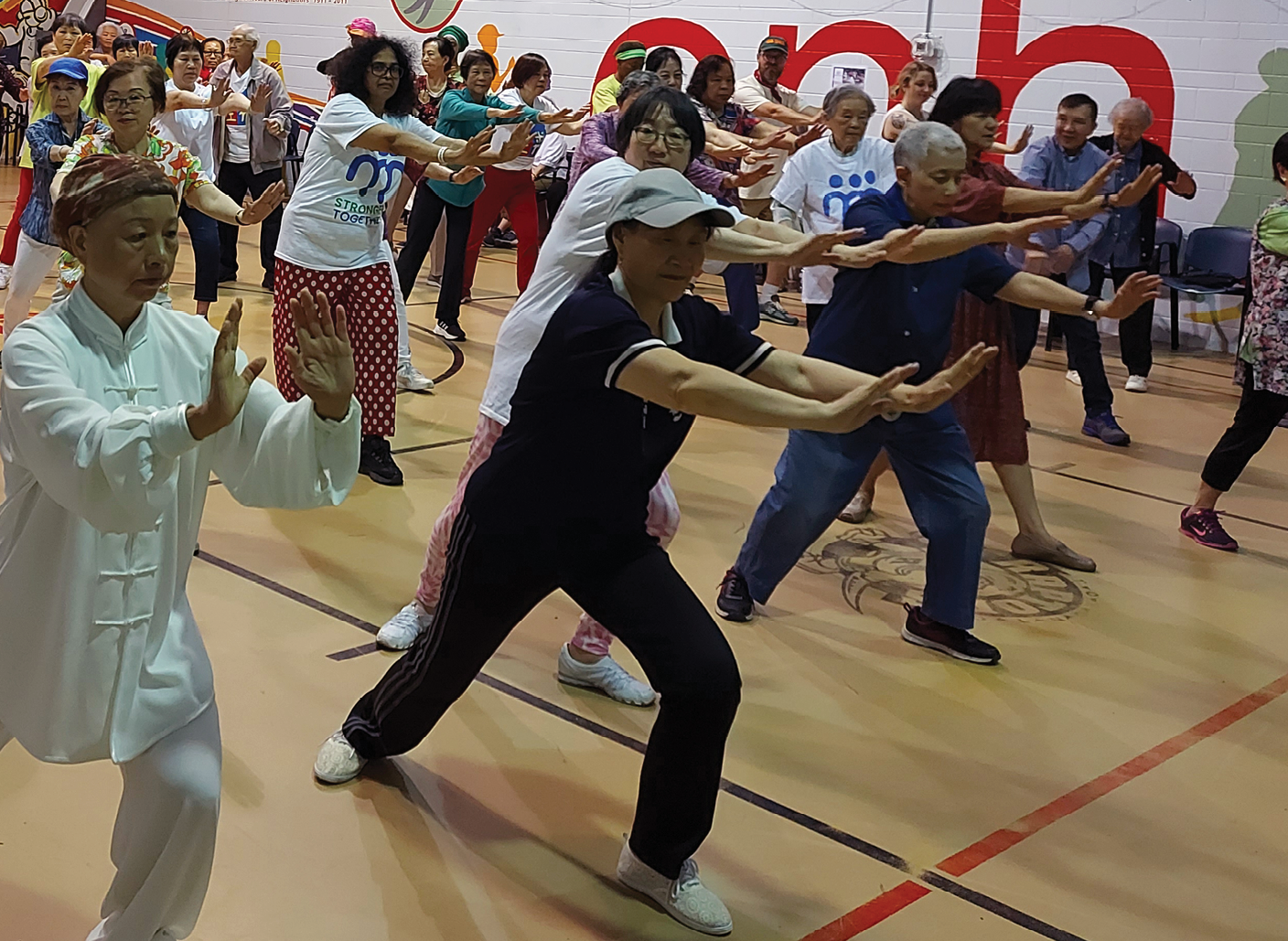 seniors and friends doing Tai Chi in a gym