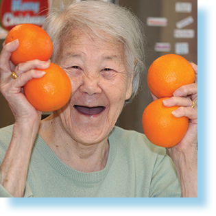 smiling elderly woman holding oranges