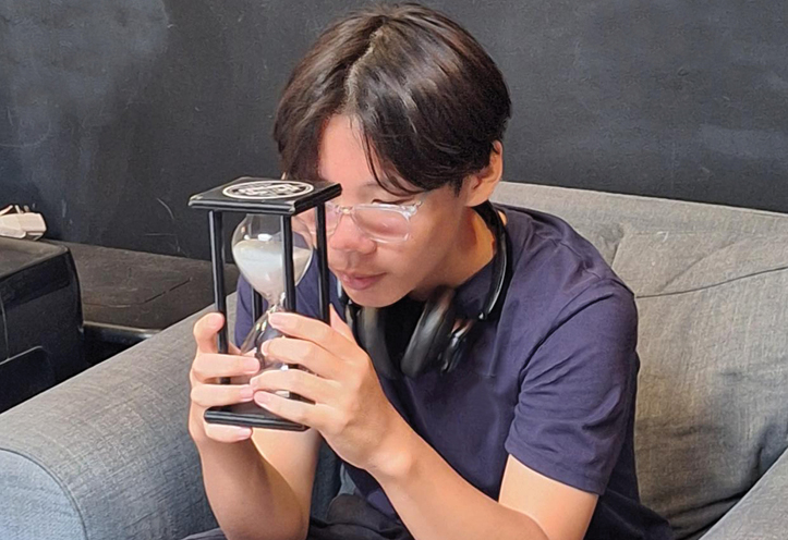 young man sitting on a couch holding an hourglass