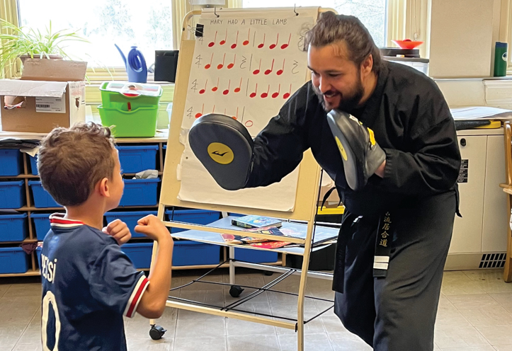 young man teaching a child how to box in an extracurricular sports program