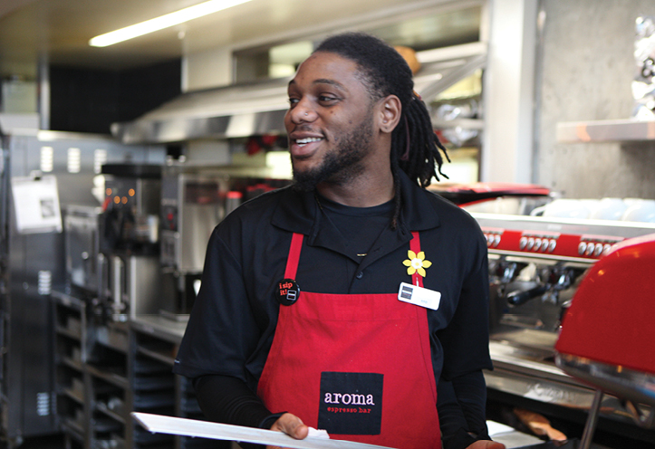 Man in a cafe, wearing an apron and smiling