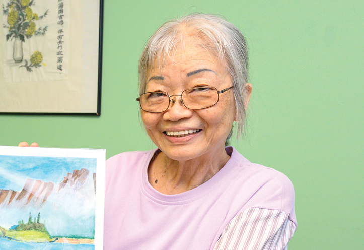 smiling elderly woman holding artwork