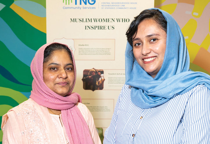 two women standing in front of a sign with the title 