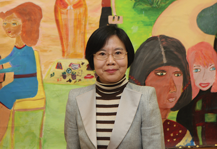 Woman standing in front of a mural, smiling