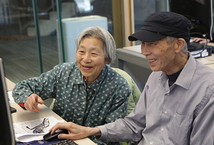 two smiling seniors at a computer