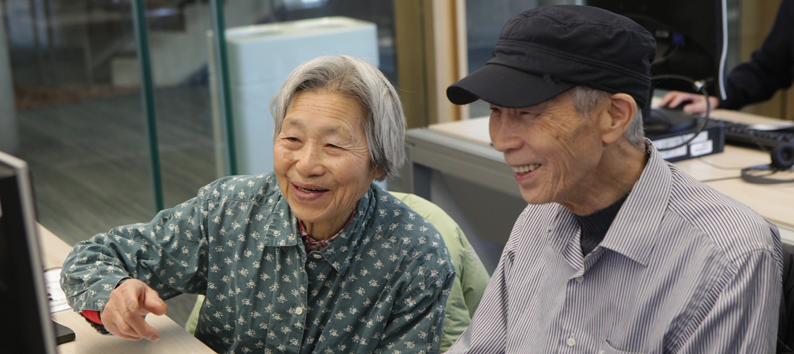 two smiling seniors looking at a computer