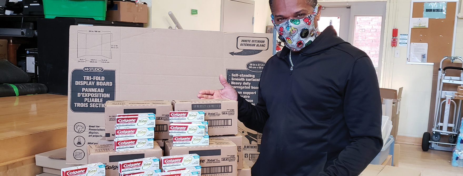 man giving boxes of Colgate toothpaste as in-kind donations