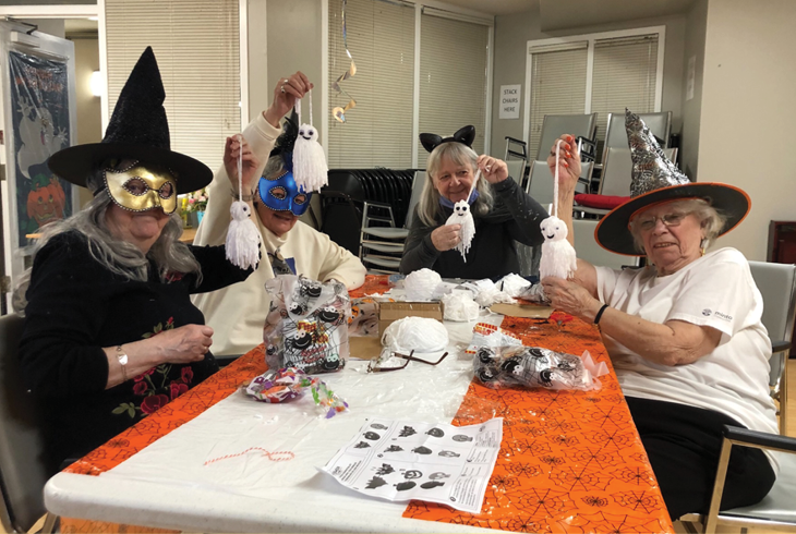 seniors in supportive housing dressed up for Halloween and doing arts and crafts