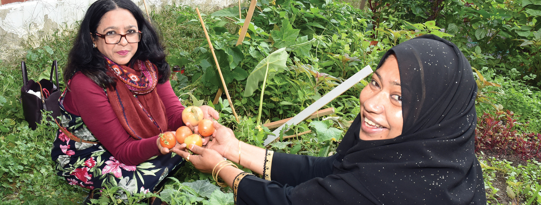 two women helping each other in the Community Garden