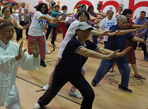 seniors and friends doing Tai Chi in a gym